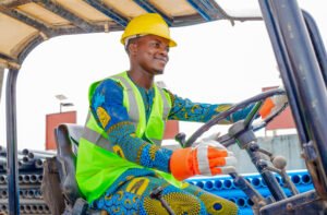 Ouvrier IBP équipé d’un EPI conduisant une grue sur le site industriel de Cotonou