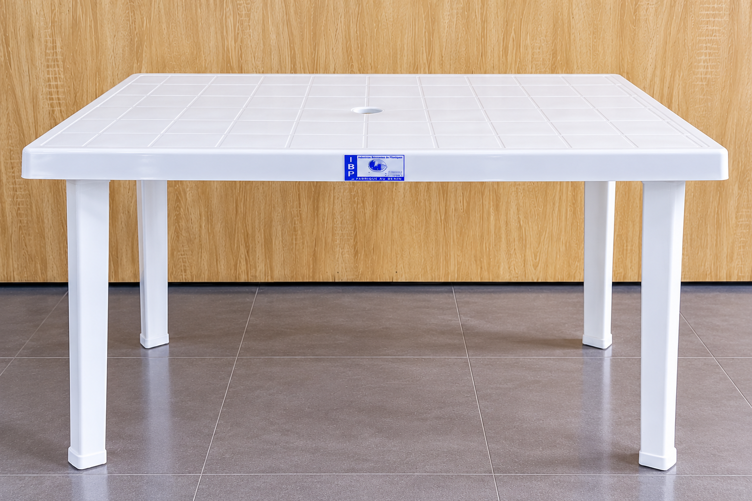 Table rectangulaire en plastique blanc IBP, avec quatre pieds, plateau quadrillé et trou central pour parasol, fabriquée au Bénin.